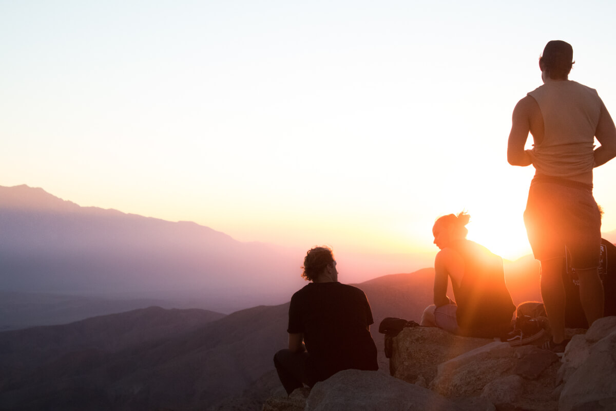 four people near the cliff on golden hour